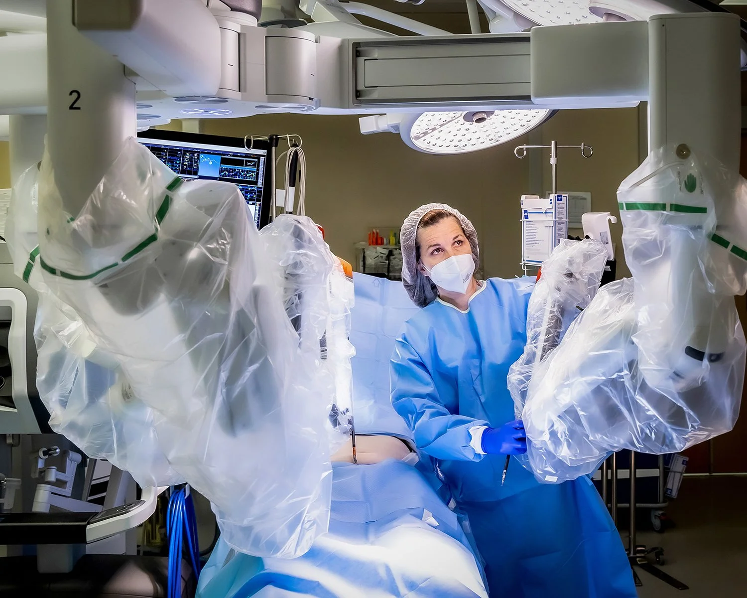 Female Doctor in Blue scrubs and Mask in High Tech Operating Room with Robotic Arms