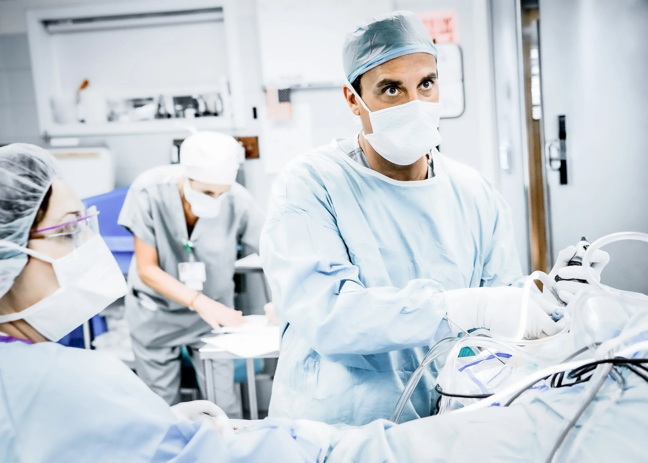 Surgeon in Blue Scrubs Performing Arthroscopic Surgery in Operating Room with Help of 2 Nurses.