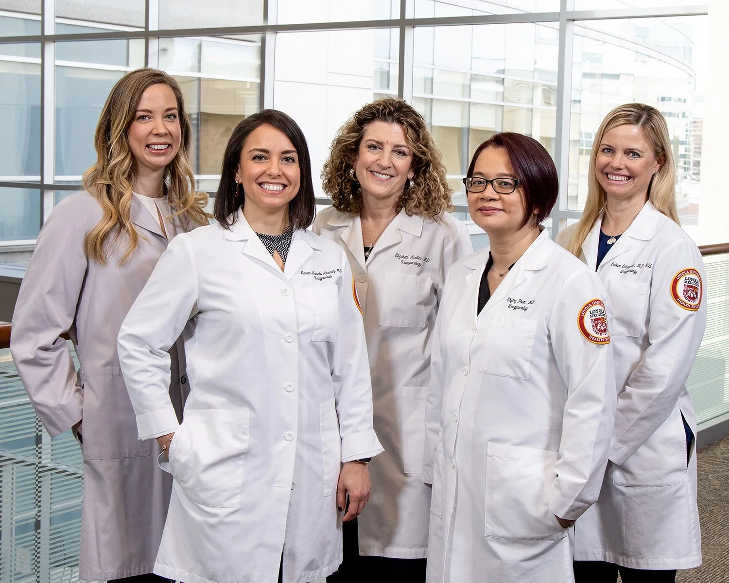 Group Portrait of Female Doctors in White Lab Coats with Big Windows Behind