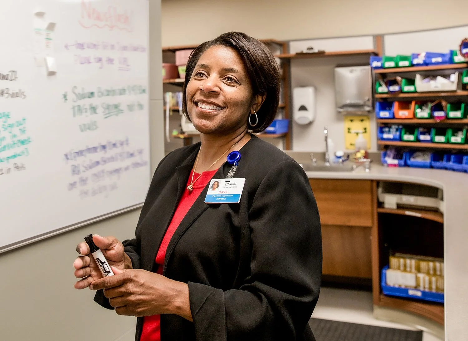 African American Female Nurse Smiling and Looking Off Camera in the Pharmacy Section of a Hospital.  Medical Lifestyle Photography
