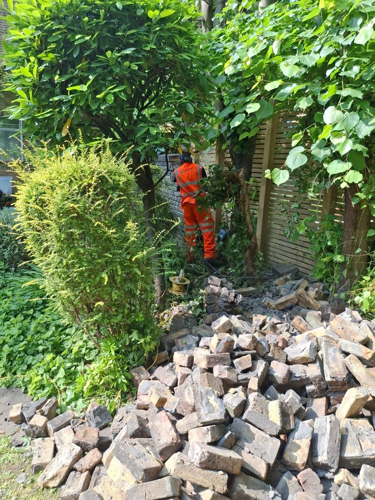 worker-demolishing-garden-wall-manually.JPG