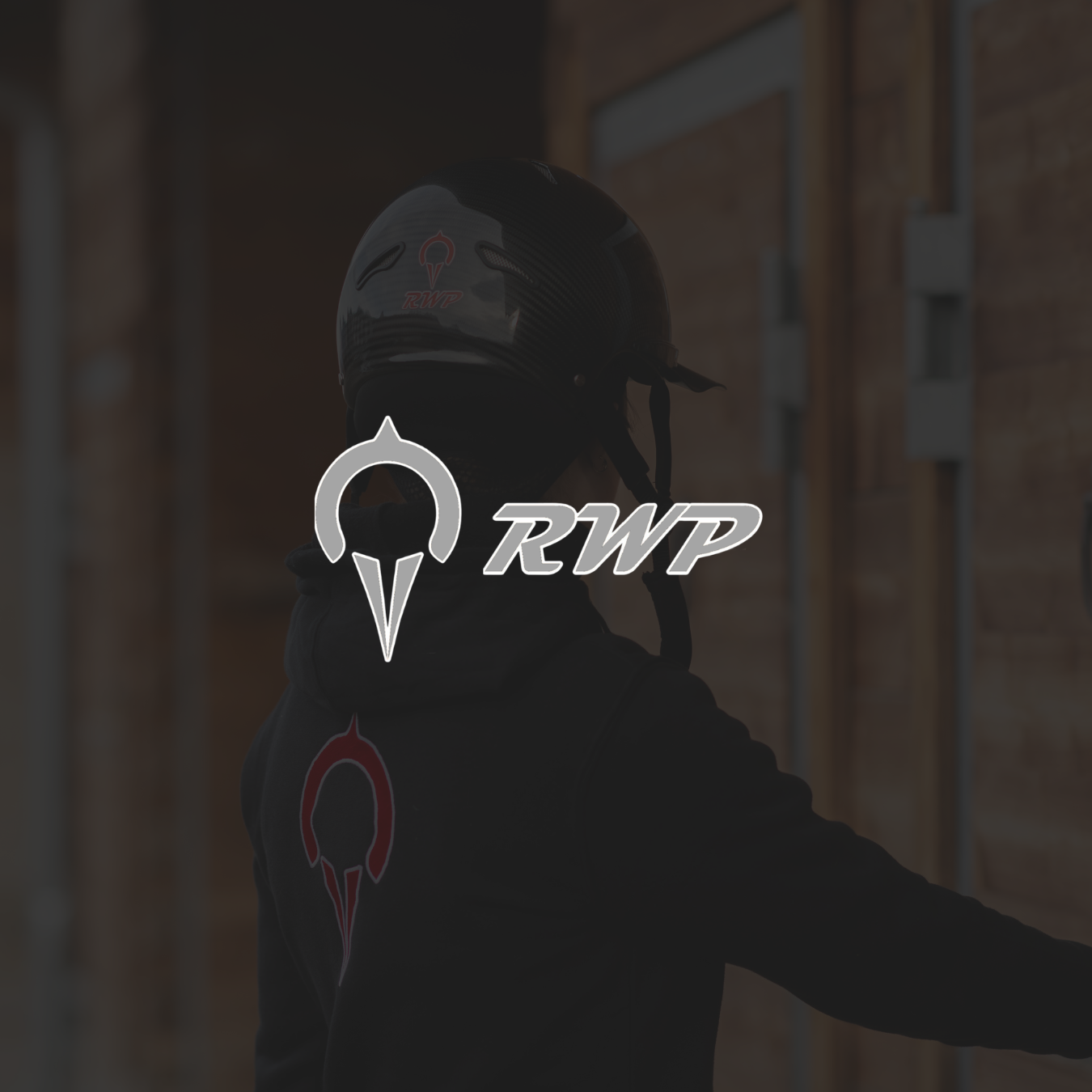 Person mit Motorradhelm und RWP-Logo auf dem Rücken, Hintergrund aus Holzplatten.