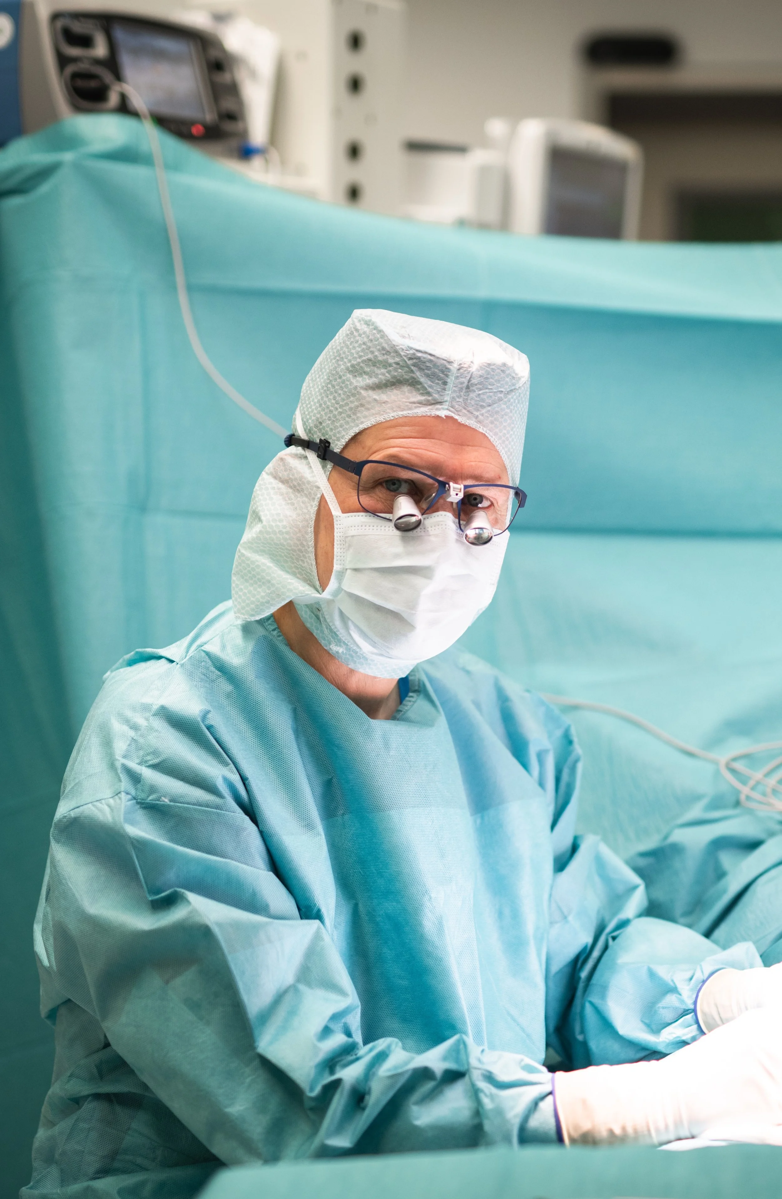 Ein Arzt in Operationskleidung und Maske während einer Operation im Operationssaal.