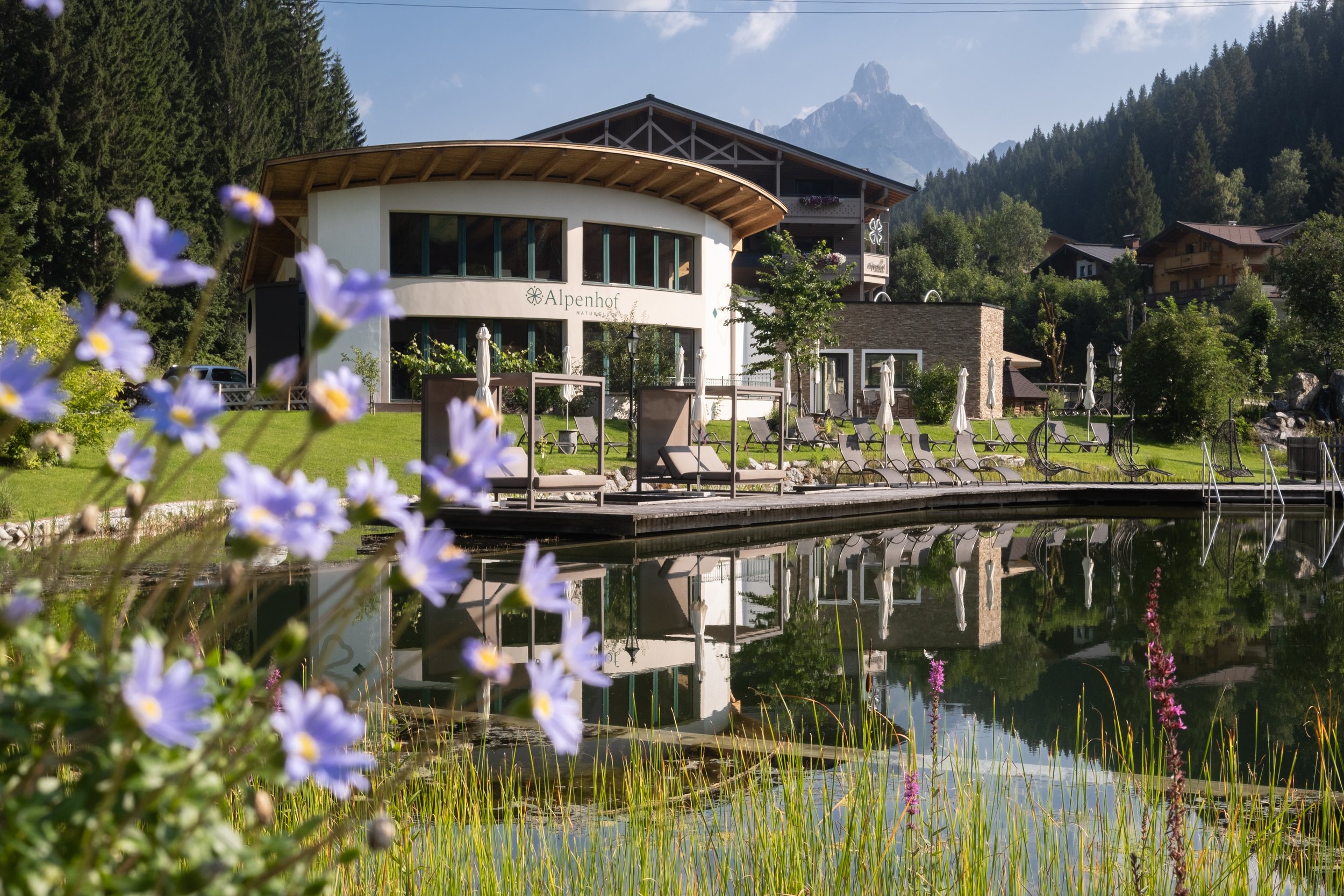 Alpenhotel mit Blick auf Berge, umgeben von Bäumen, mit Garten und Wasser