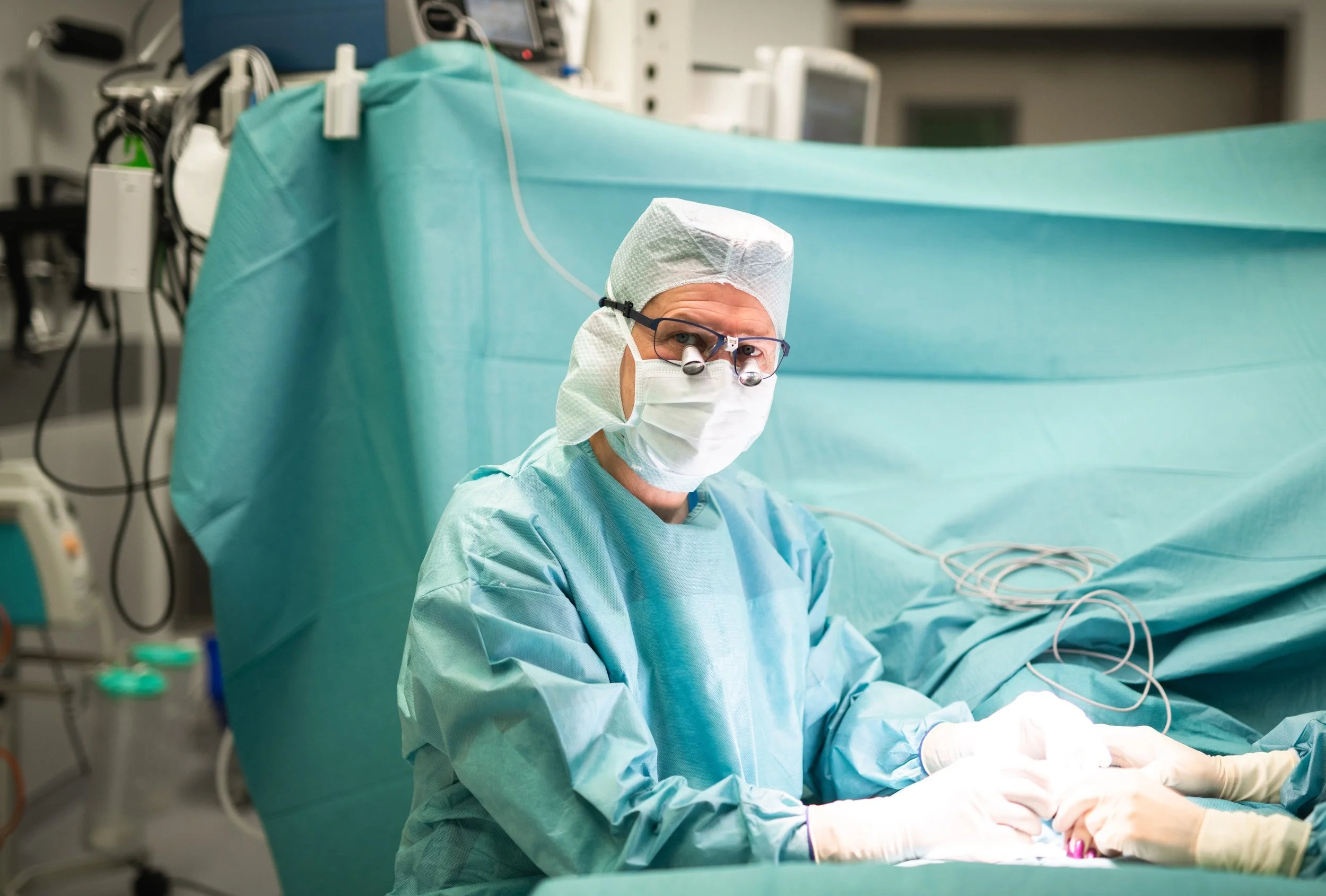 Ein Chirurg in Operationskleidung arbeitet an einem Patienten im Operationssaal.