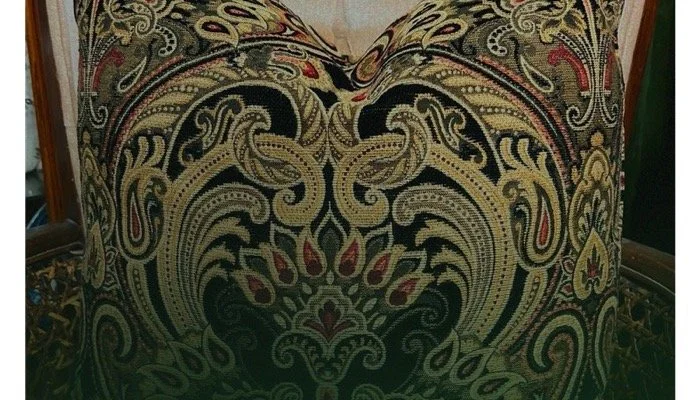 Close-up of a fabric with elaborate, detailed black, beige, red, and gold embroidery or print.