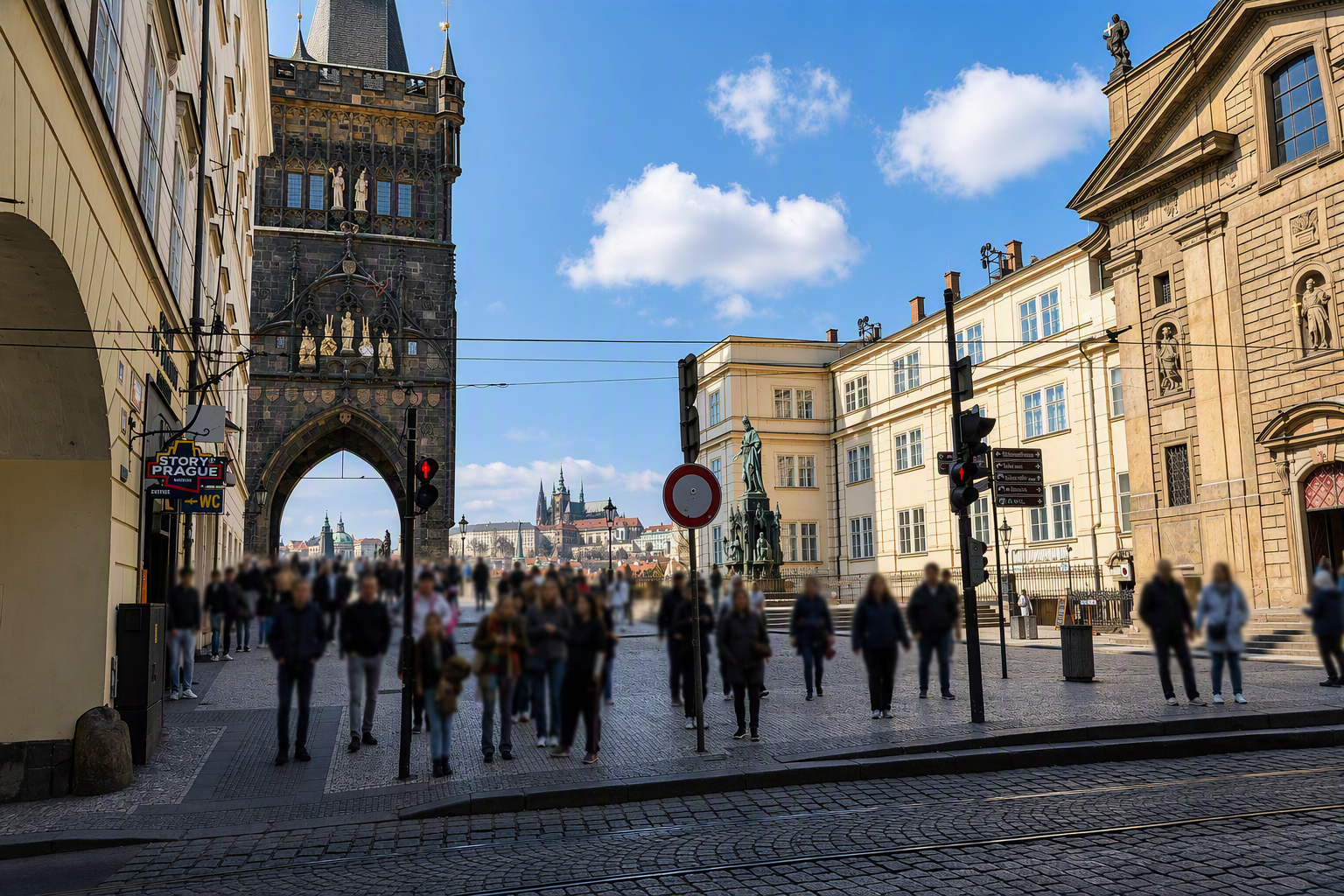 Street scene in Prague with crowd of people, historic buildings, and the Prague Castle in the background.