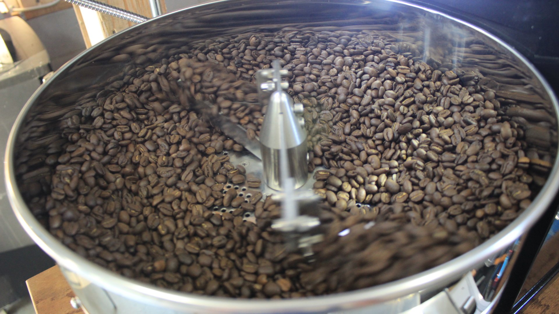 Close-up of roasted coffee beans in the cooling tray of the roaster, it has a powerful suction fan pulling air through the bottom and rotating arms to gently stir the coffee beans.