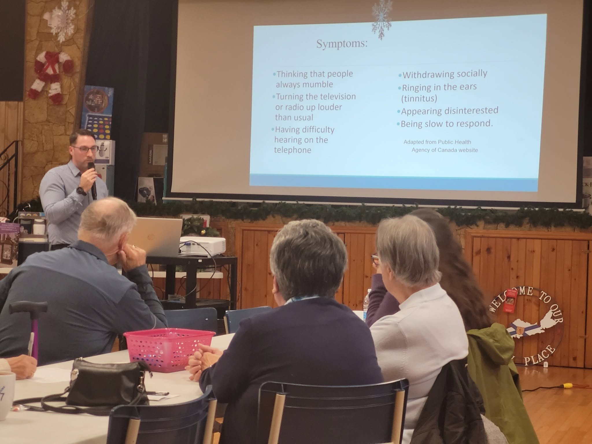 Guest speaker with a microphone presenting on hearing loss symptoms to seniors at a STAC meeting