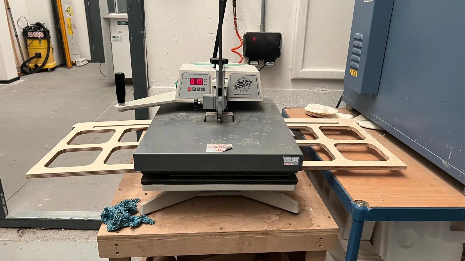 A woodworking table with a laser engraving machine and wooden frames, in a woodworking workshop.