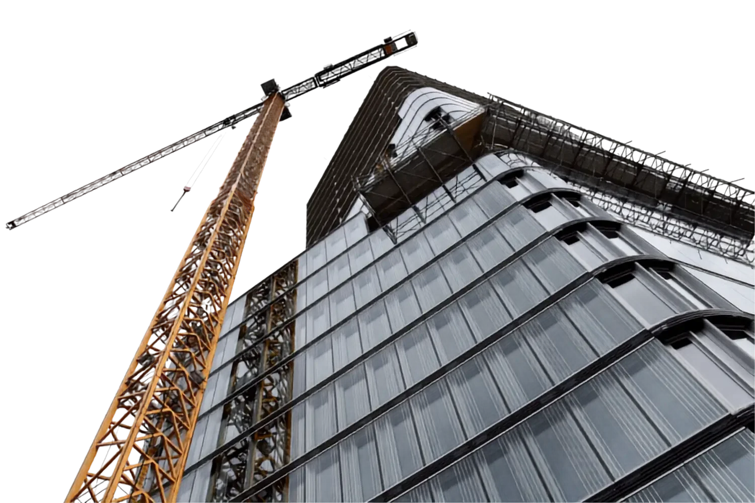 A high-rise building under construction with a tall yellow crane beside it at night.