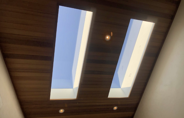 Ceiling with two skylights, wooden panels, and recessed lighting