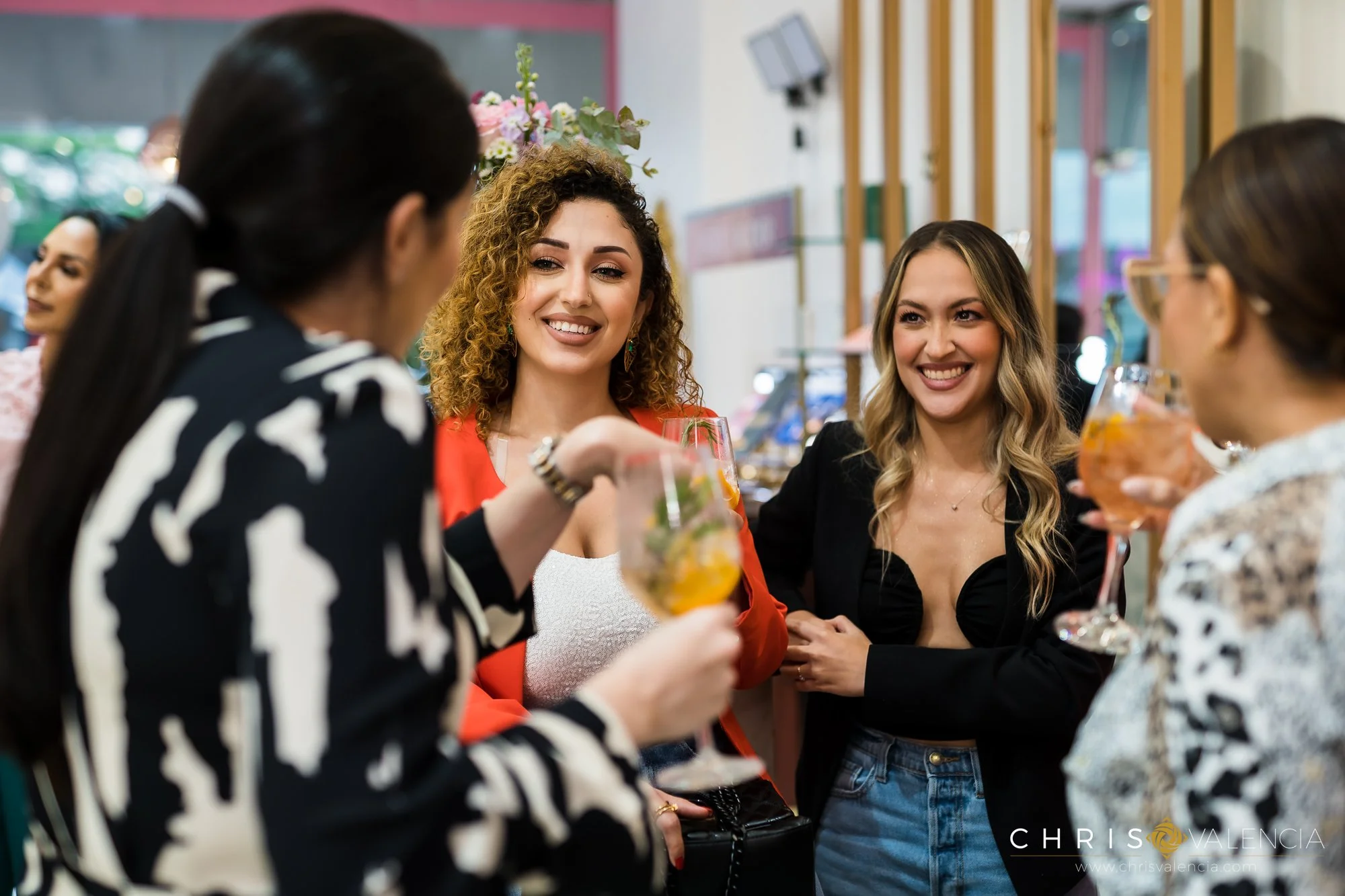 Grupo de mujeres sonriendo y brindando con copas de cóctel en un ambiente social.