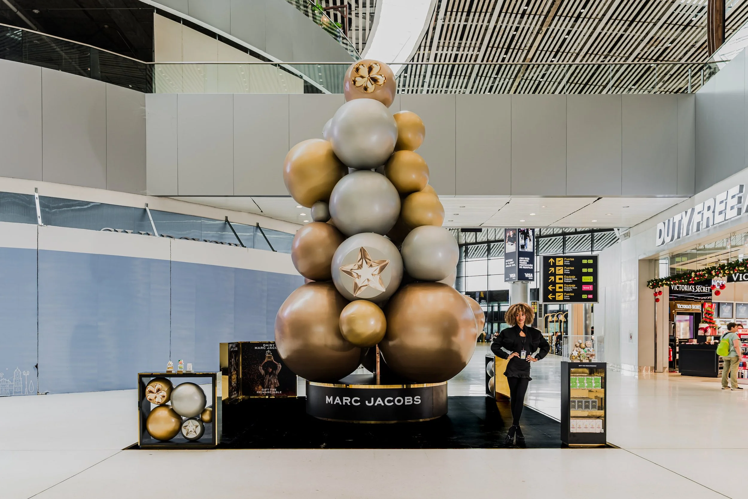 Decoración navideña con bolas doradas y plateadas en un centro de compras.