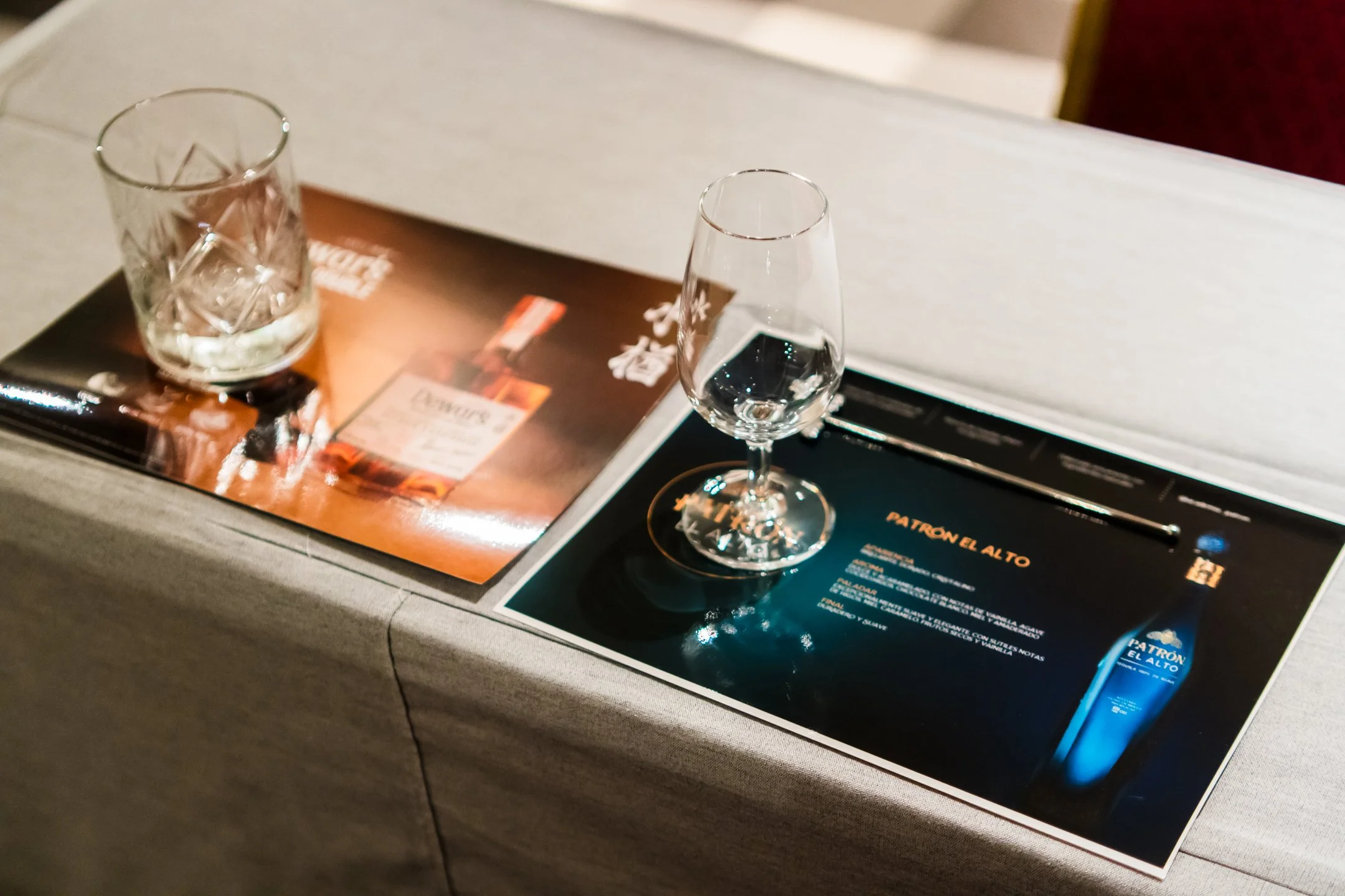 Dos vasos de cristal, uno con agua y hielo, el otro vacío, sobre una mesa con menús y promociones del restaurante en español.