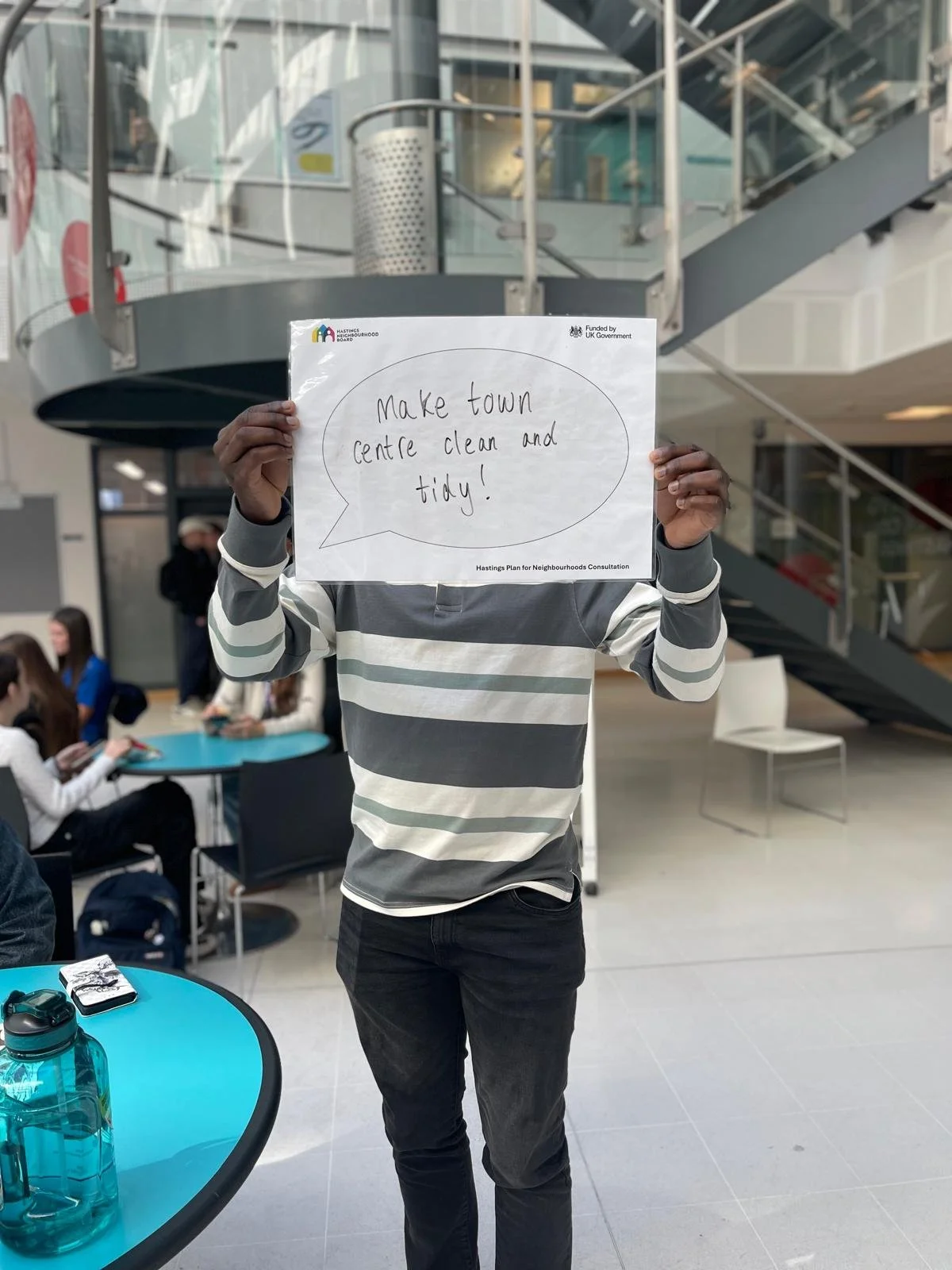 College student holding a sign which reads 'Make town centre clean and tidy!'.