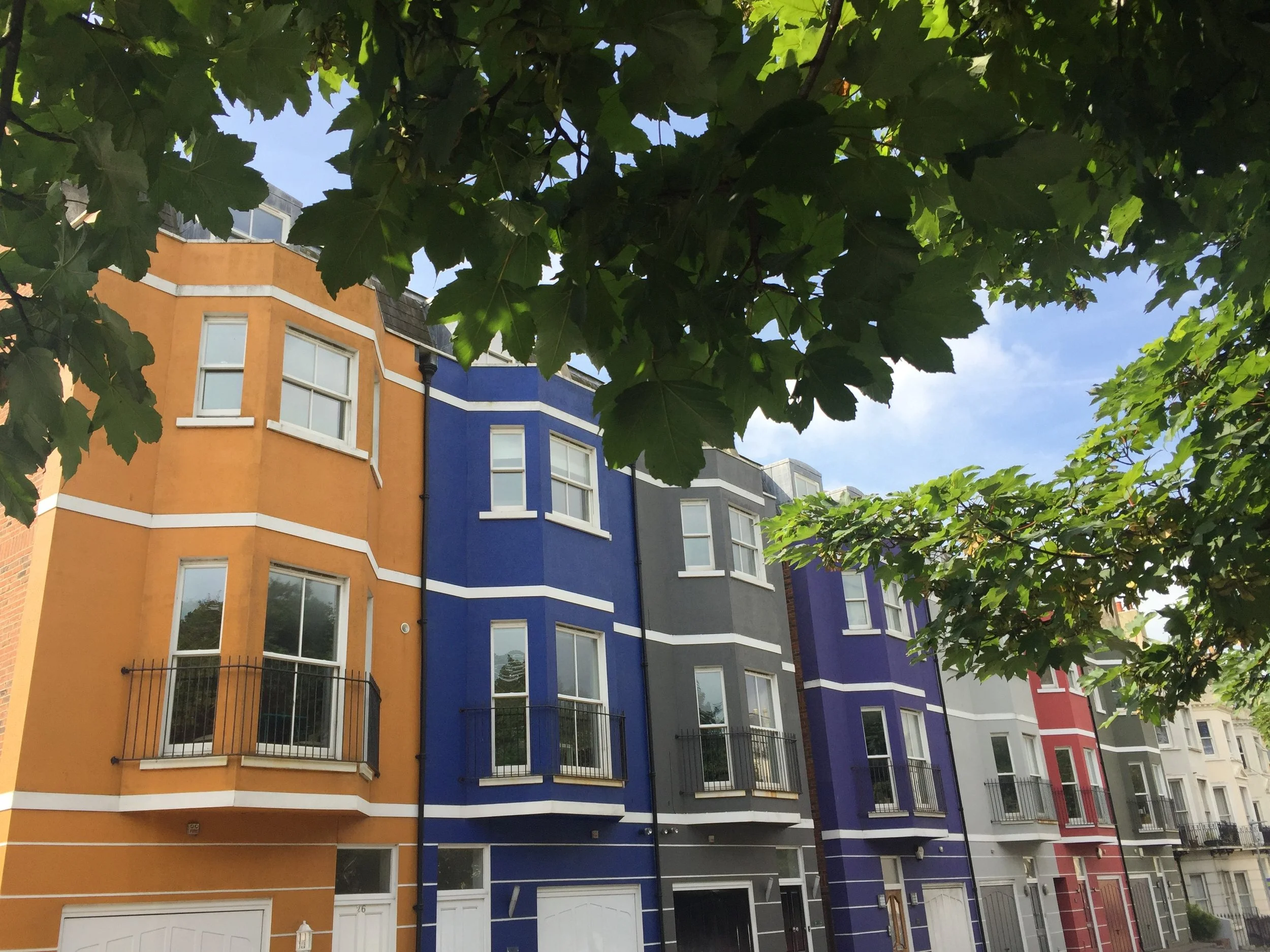 Row of townhouses each painted a bright colour.