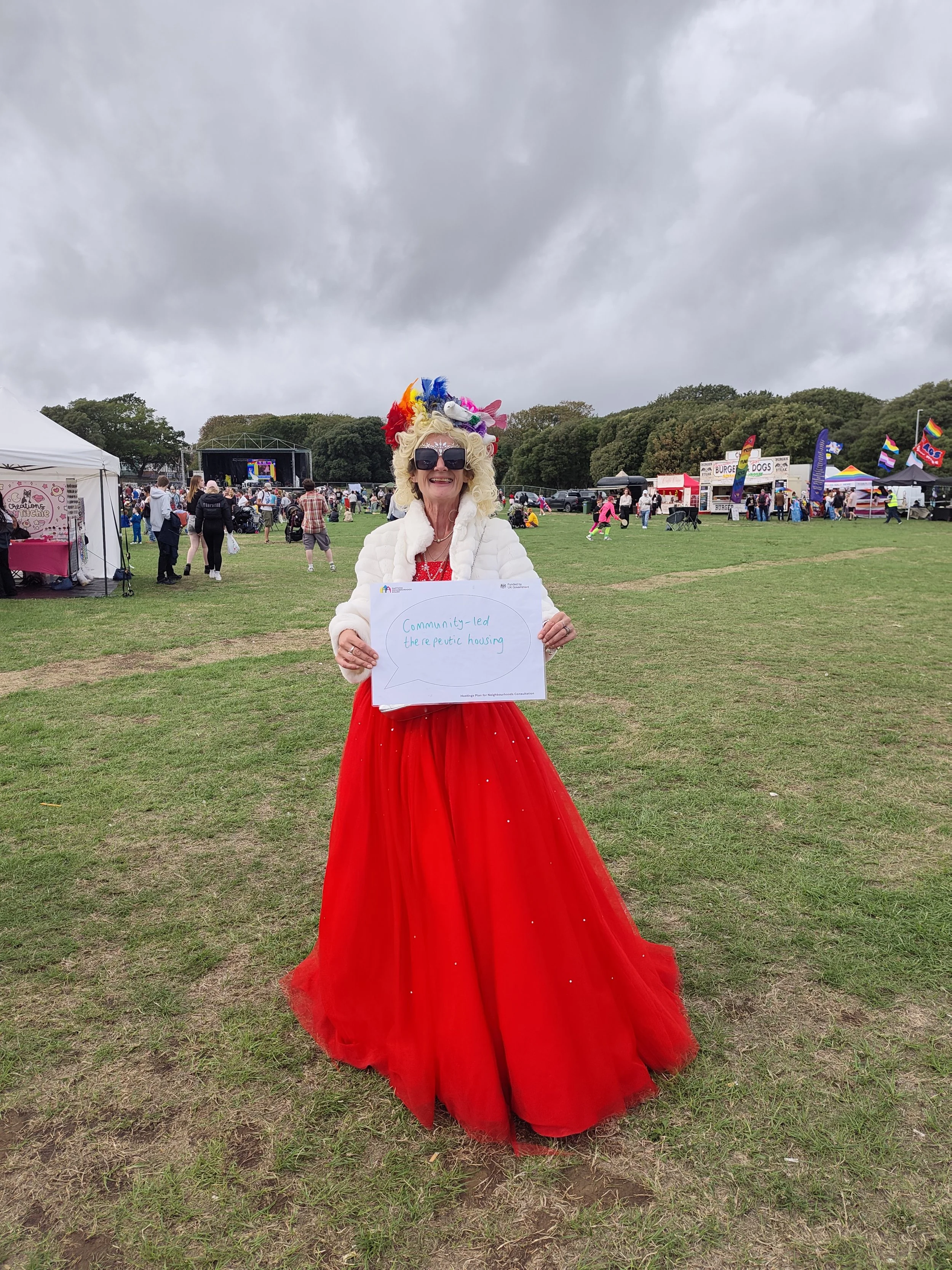 Woman holding a sign which reads 'Community-led theraputic housing'.