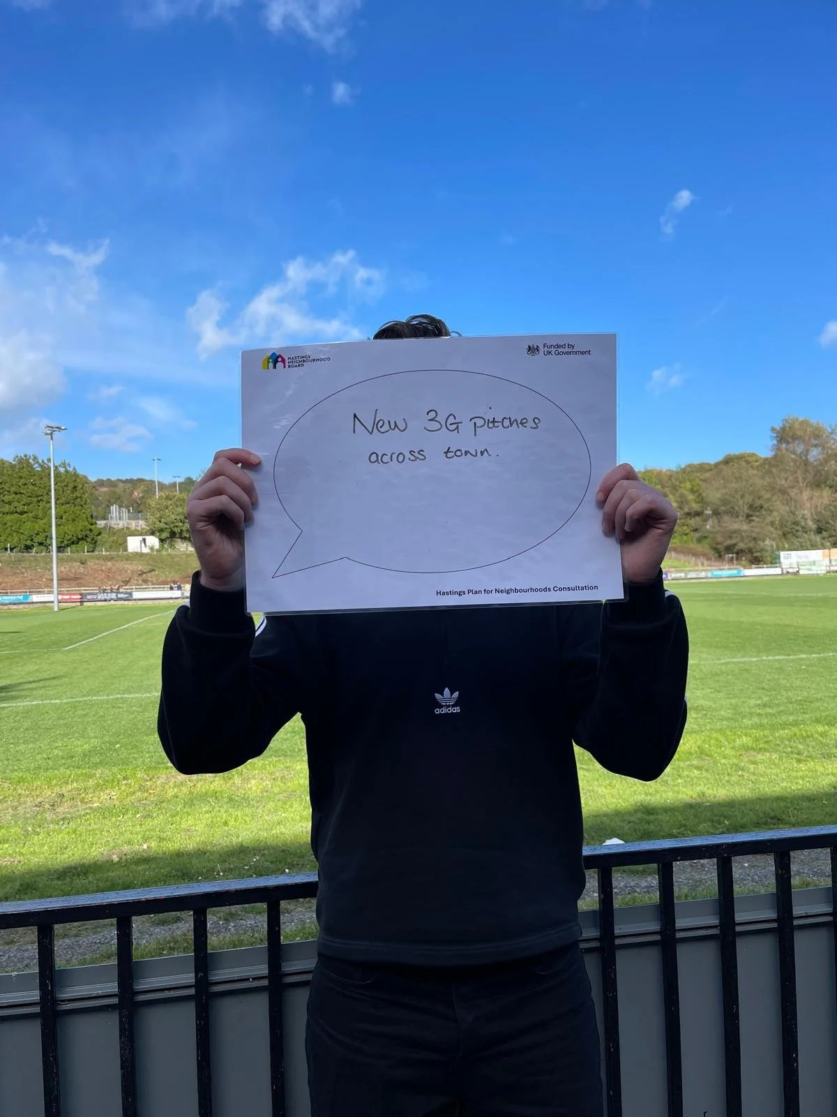 Student holding up a sign which reads 'New 3G pitches across town'.