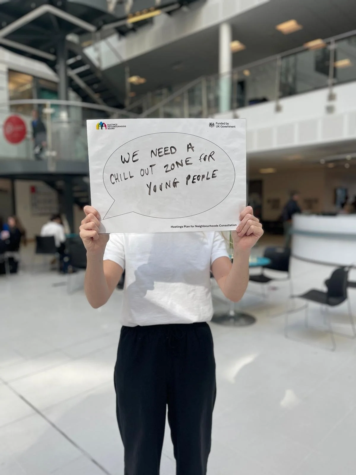College student holding a sign which reads 'We need a chill out zone for young people'.