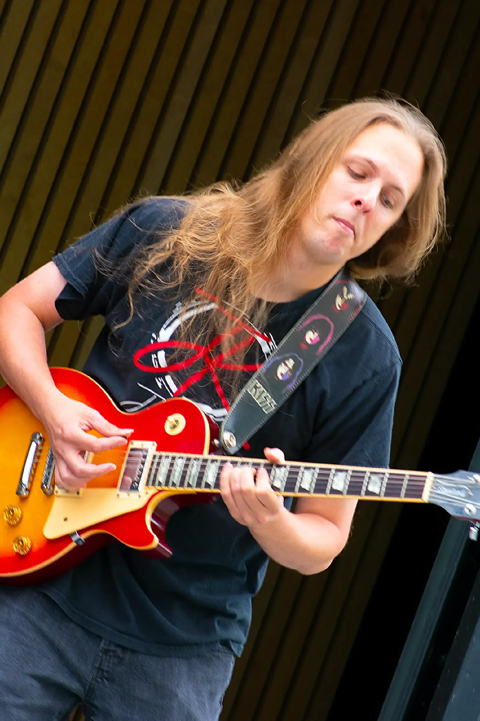 A man with long hair playing an electric guitar.