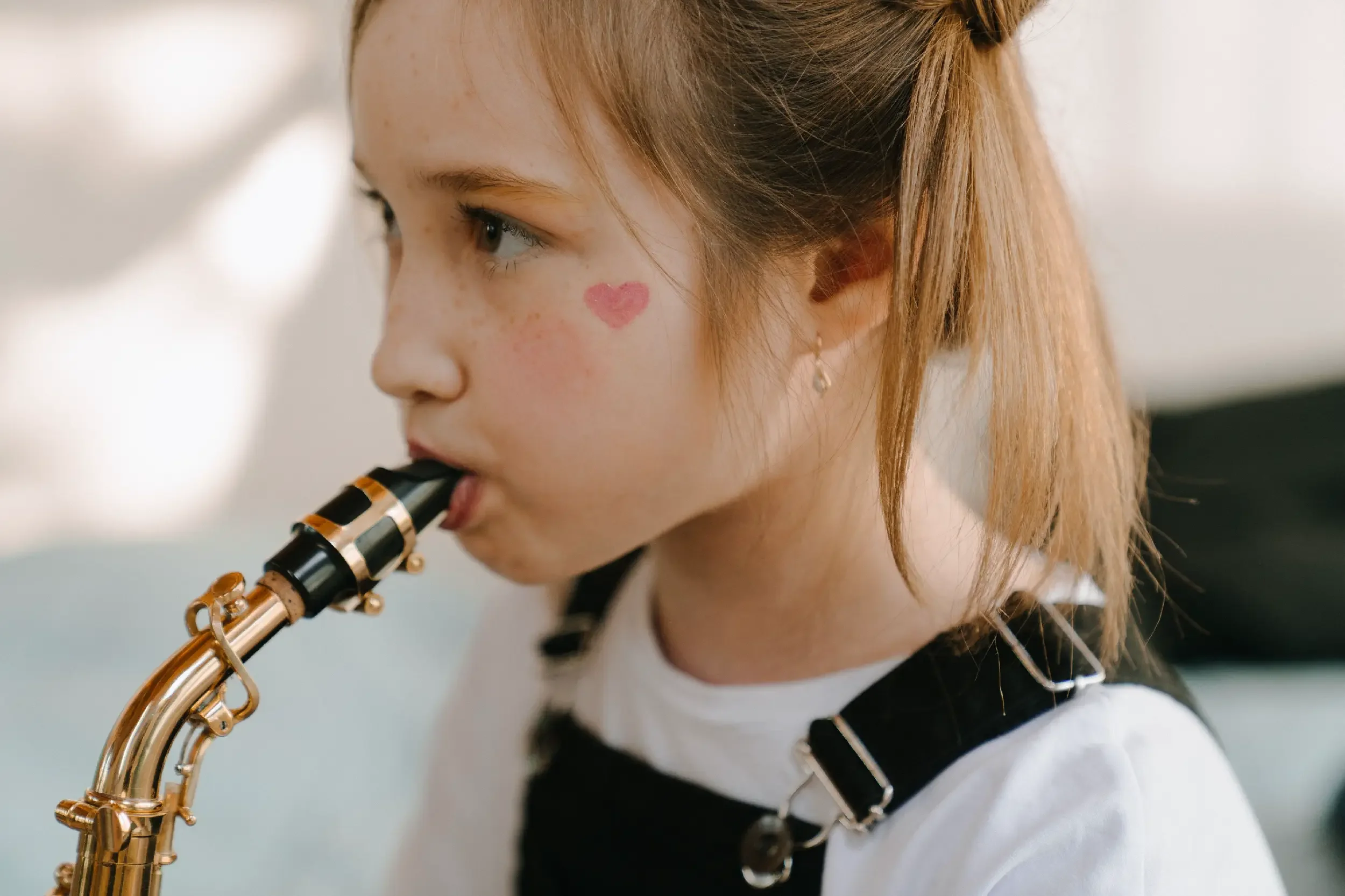 A young woman with light skin and red hair tied back playing a clarinet.