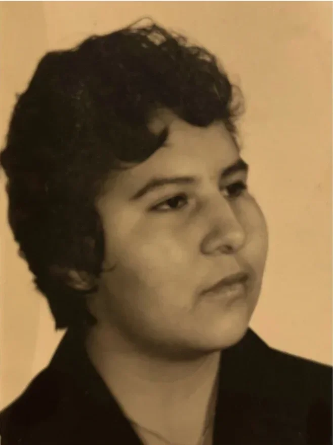 Black and white portrait of a young person with dark, curly hair, looking off to the side with a serious expression.