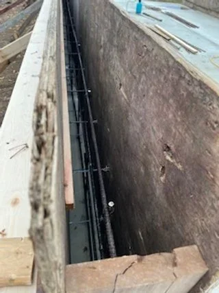 Construction site with exposed rebar in a concrete foundation.