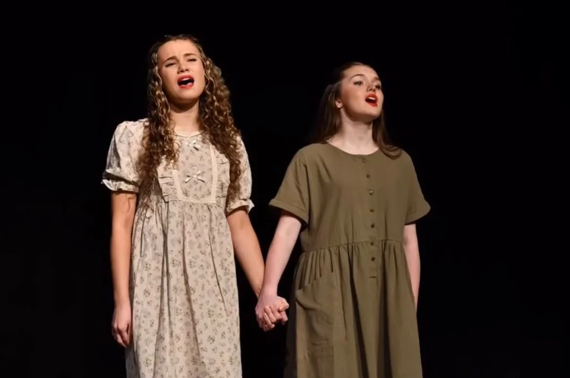Two young girls singing on stage in musical theatre duet