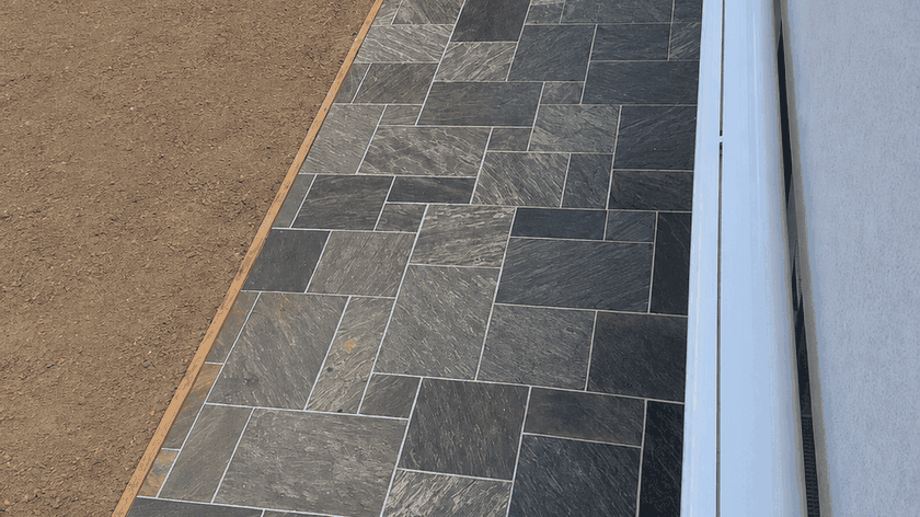 Exterior porch with dark gray stone tiles and a light gray wall.