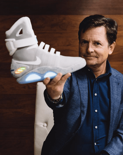 Man in a blue blazer holding a futuristic white sneaker with glowing sole