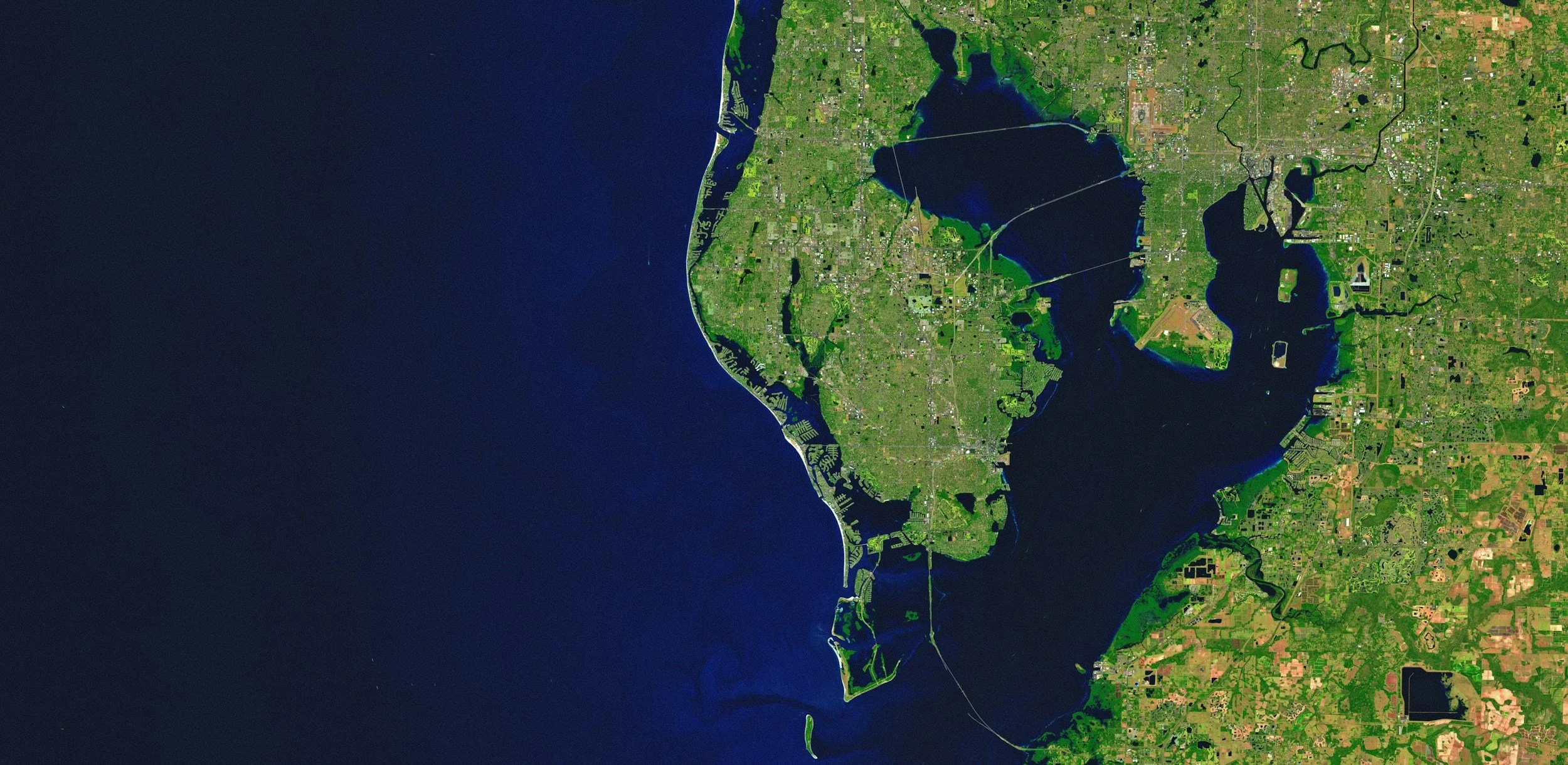 Satellite image of a large landmass (Tampa, FL area) with a coastline on the left, showing lakes, rivers, and green urban and rural areas.