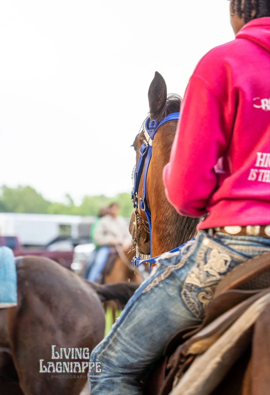 Young rider in a bright pink shirt seated on a horse at a Louisiana community gathering.