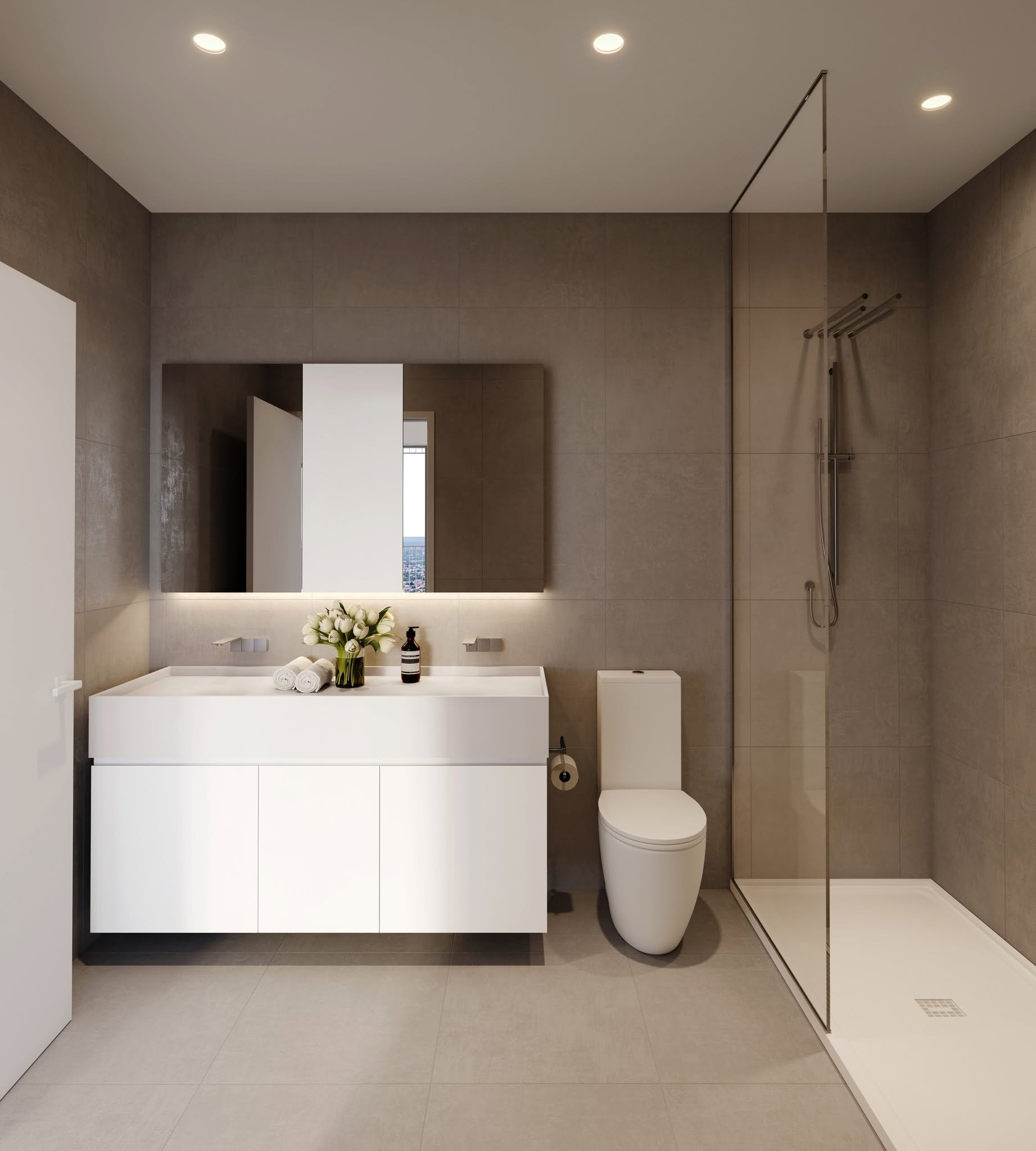 Intérieur moderne d'une salle de bain avec un lavabo blanc, un miroir, un vase avec des fleurs blanches, un robinet, un WC blanc, une cabine de douche avec porte en verre et un sol en carrelage clair.