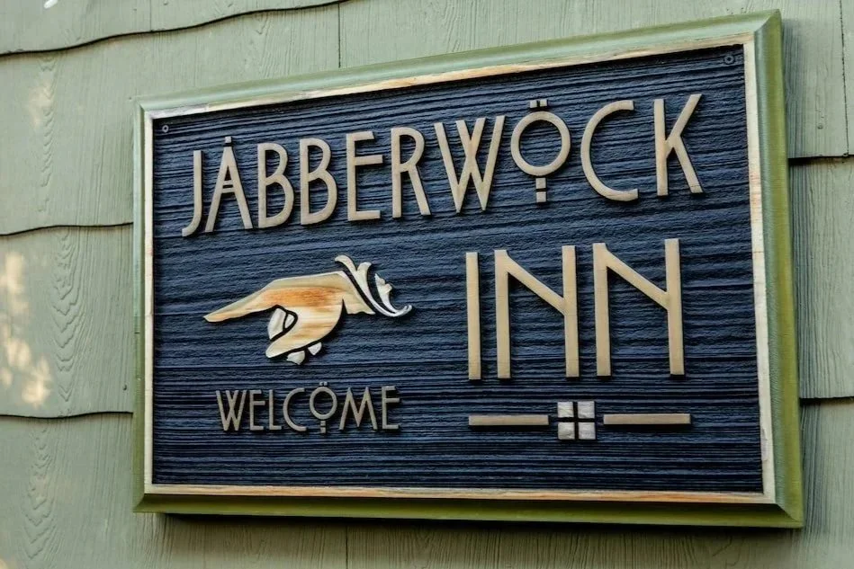 Sign for Jabberwock Inn featuring a whimsical hand pointing to the left with the word 'WELCOME' below.