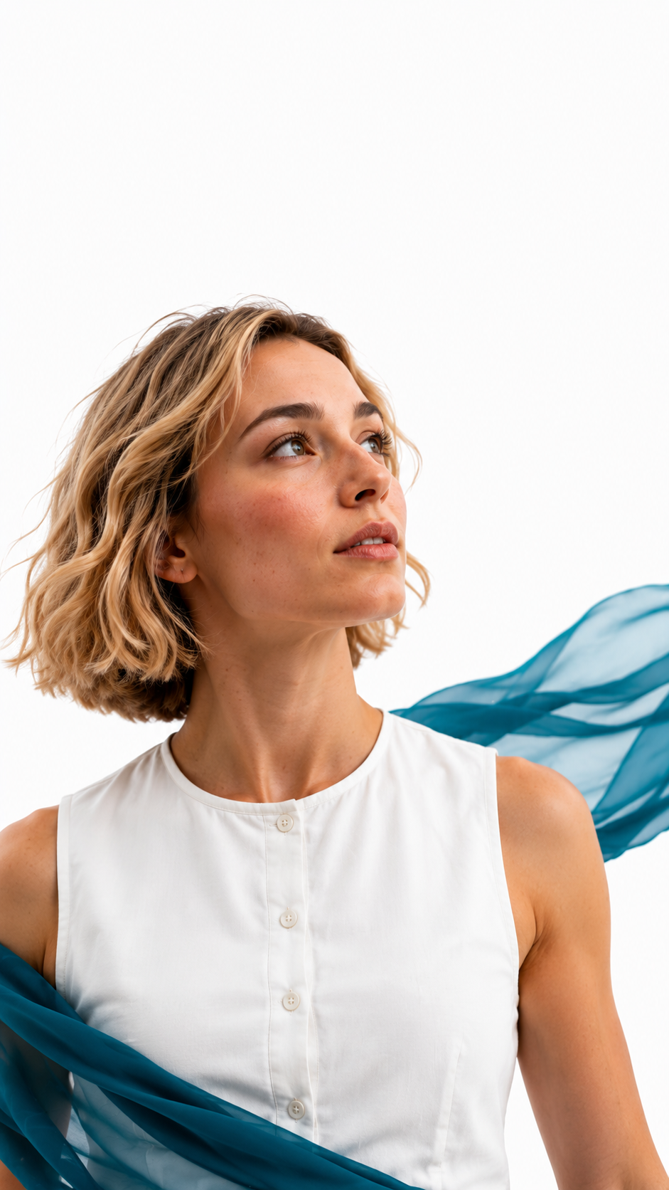 Eine Frau mit gewelltem blondem Haar trägt ein weißes ärmelloses Oberteil und blickt nach links, während hinter ihr ein transparentes blaues Tuch vor einem weißen Hintergrund fließt.
