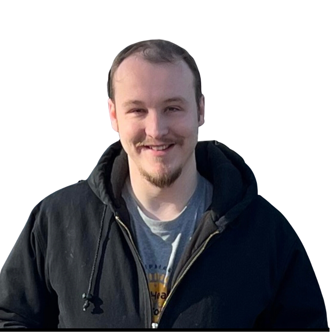 A young man, Jon Zokaites, with short brown hair and a goatee, smiling, wearing a black jacket over a gray t-shirt, against a plain white background.