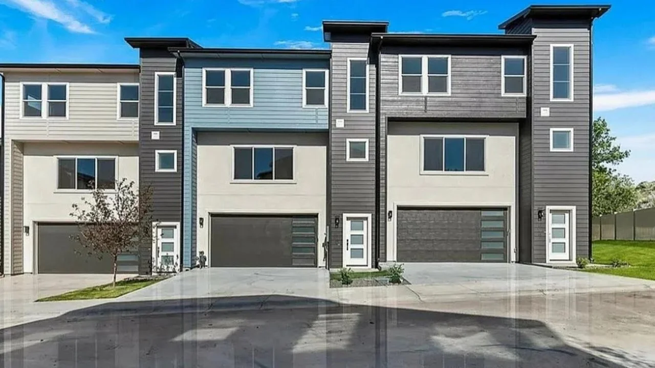 Modern townhouses with gray and white exteriors, large windows, and attached garages.