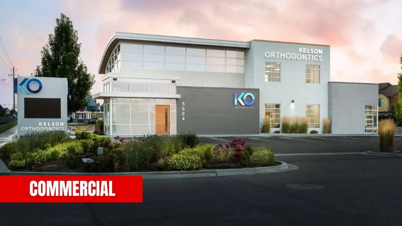 Exterior view of Kelson Orthodontics building during sunset with landscaped bushes and a sign. The building has a modern design with large windows and a sign that reads 'Kelson Orthodontics'.
