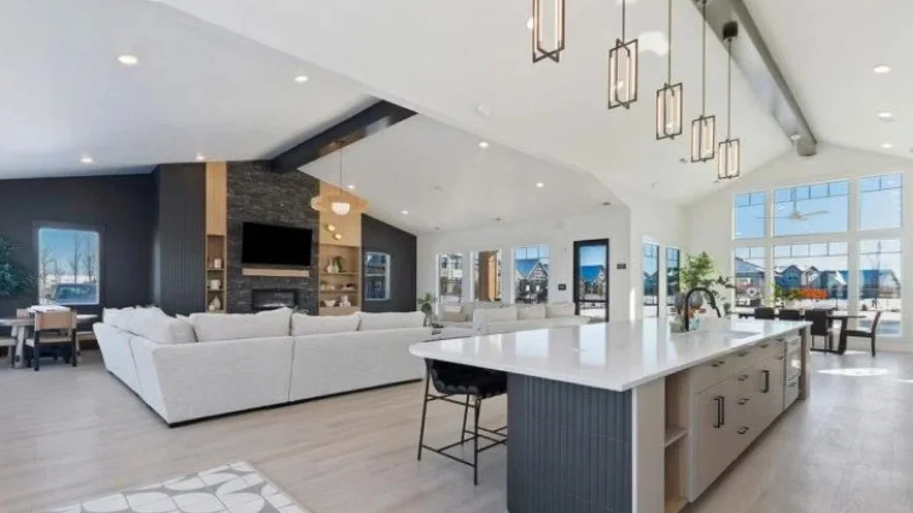 Open-concept living room and kitchen with large windows, white countertops, and modern decor.