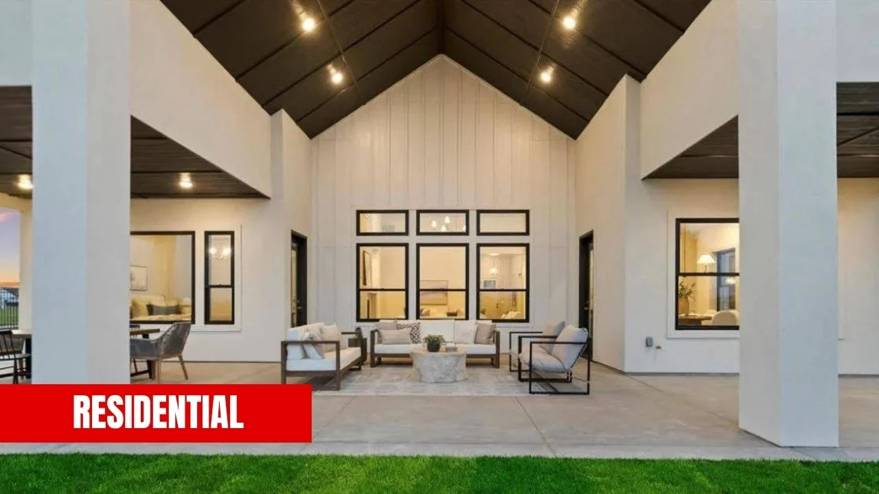 Outdoor living space of a modern residential home with seating area, large windows, and a high vaulted ceiling with recessed lighting.