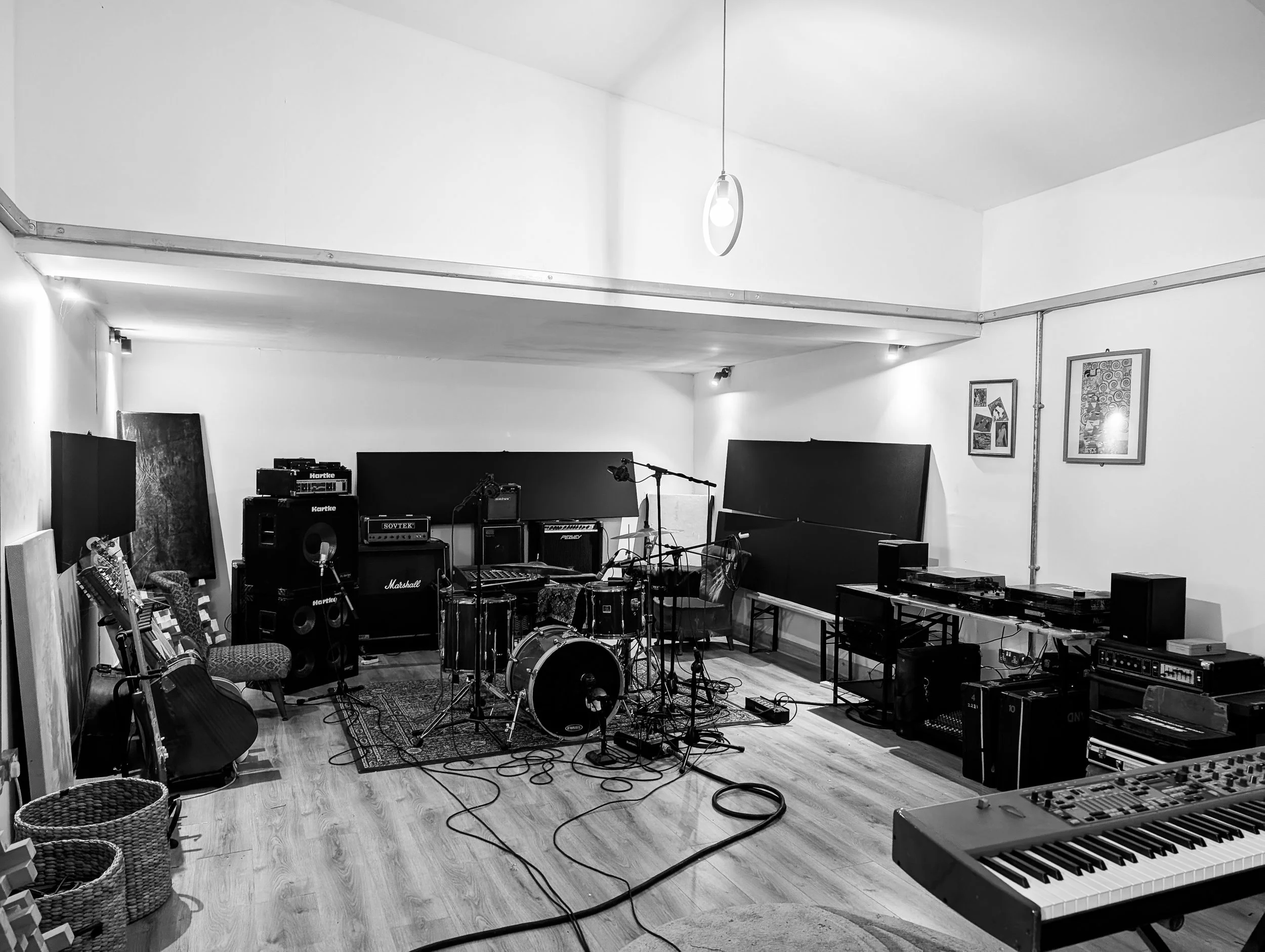Kathleen Studios Live room - A Music studio with a full drum kit, electric piano, grand piano, amplifiers, microphones, and music equipment on the floor and shelves