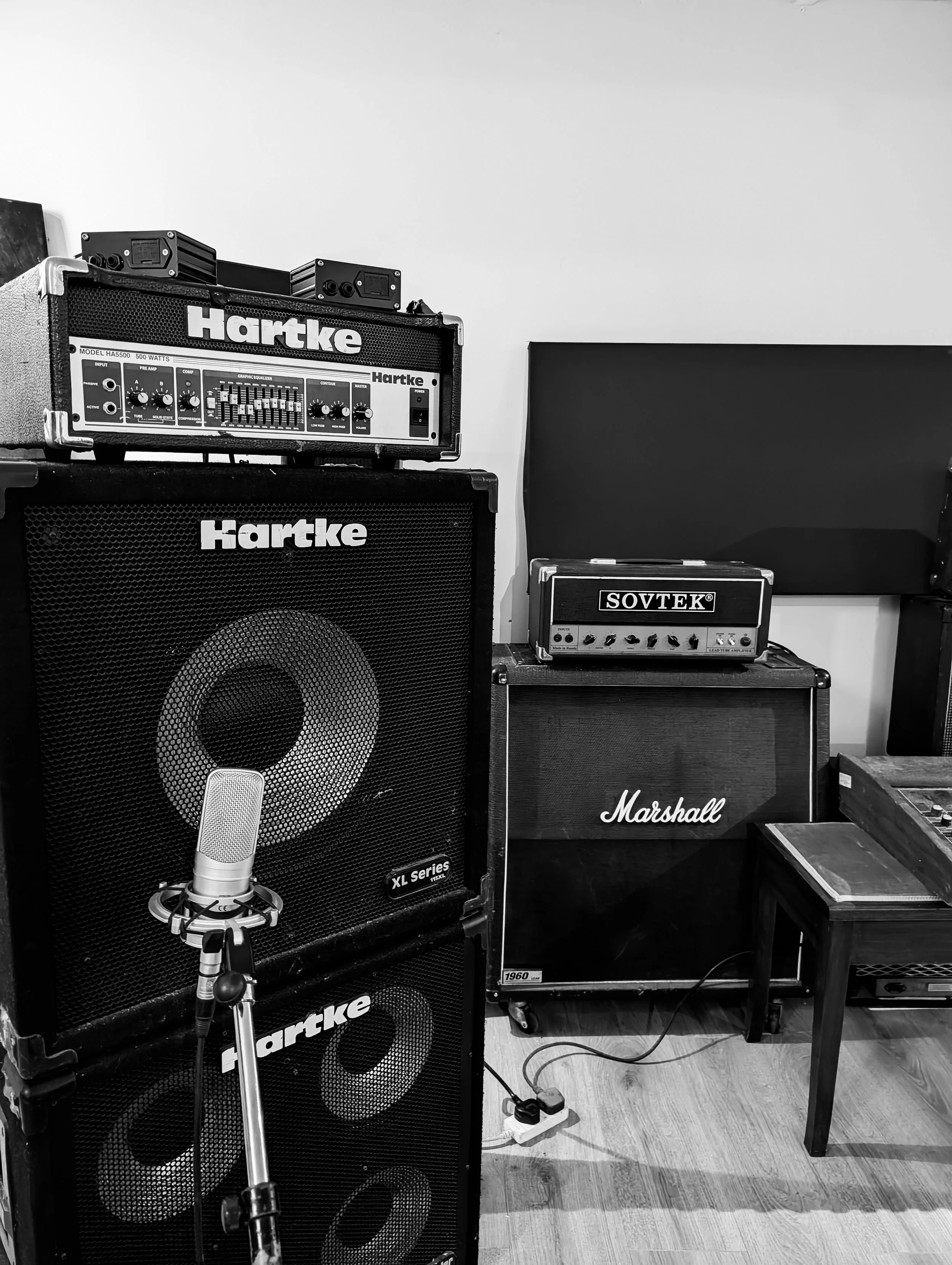 Hartke bass cab with a, Sovtek bass amplifier, Marshall speaker, and a condenser microphone on a stand.