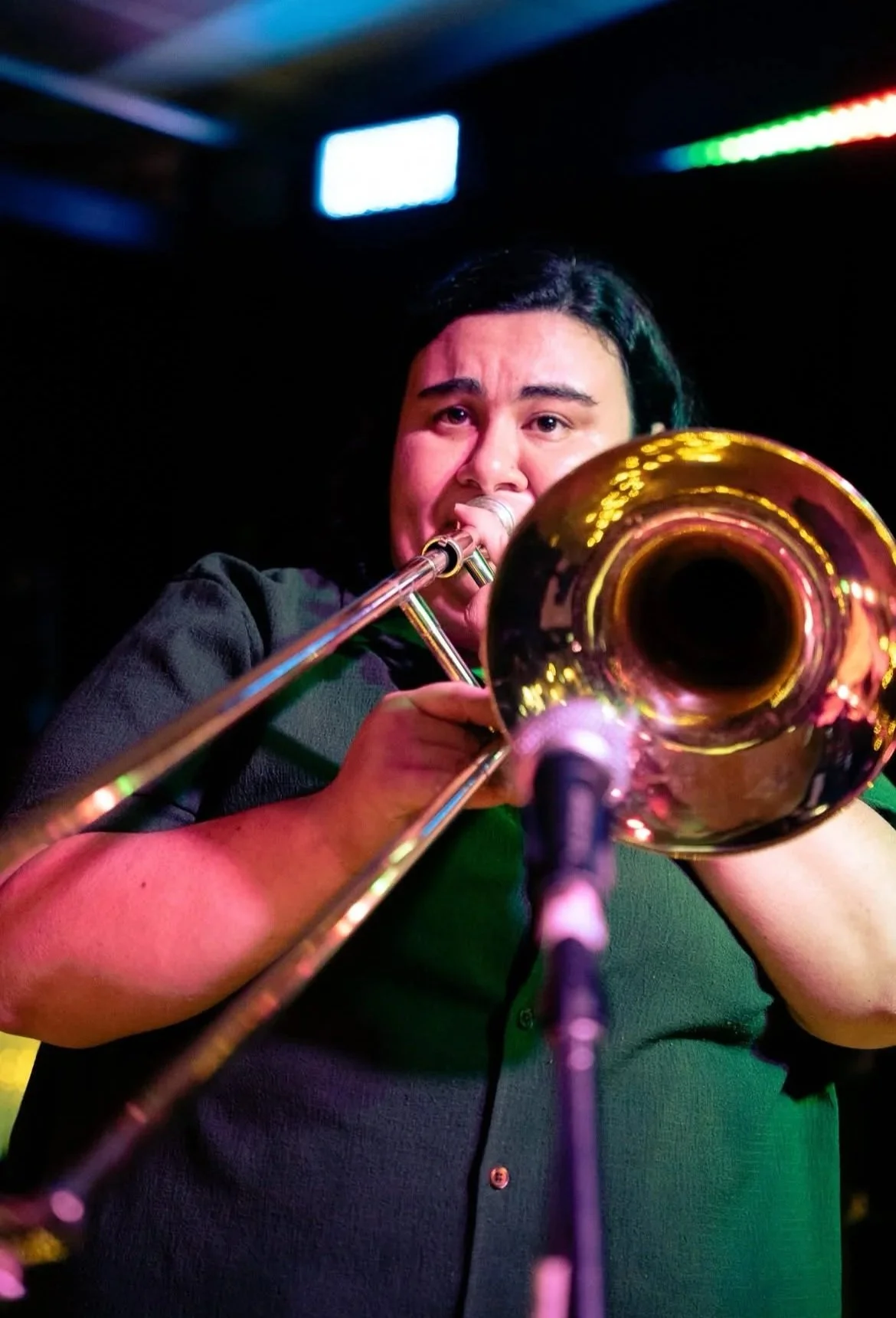 A person playing trumpet during a live performance with colorful stage lighting.