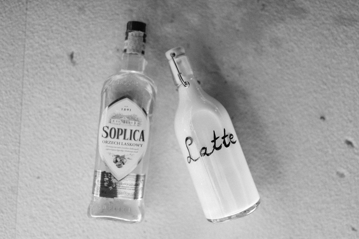 A bottle of Soplica liqueur and a glass bottle labeled "Latte" hanging on a textured ceiling.