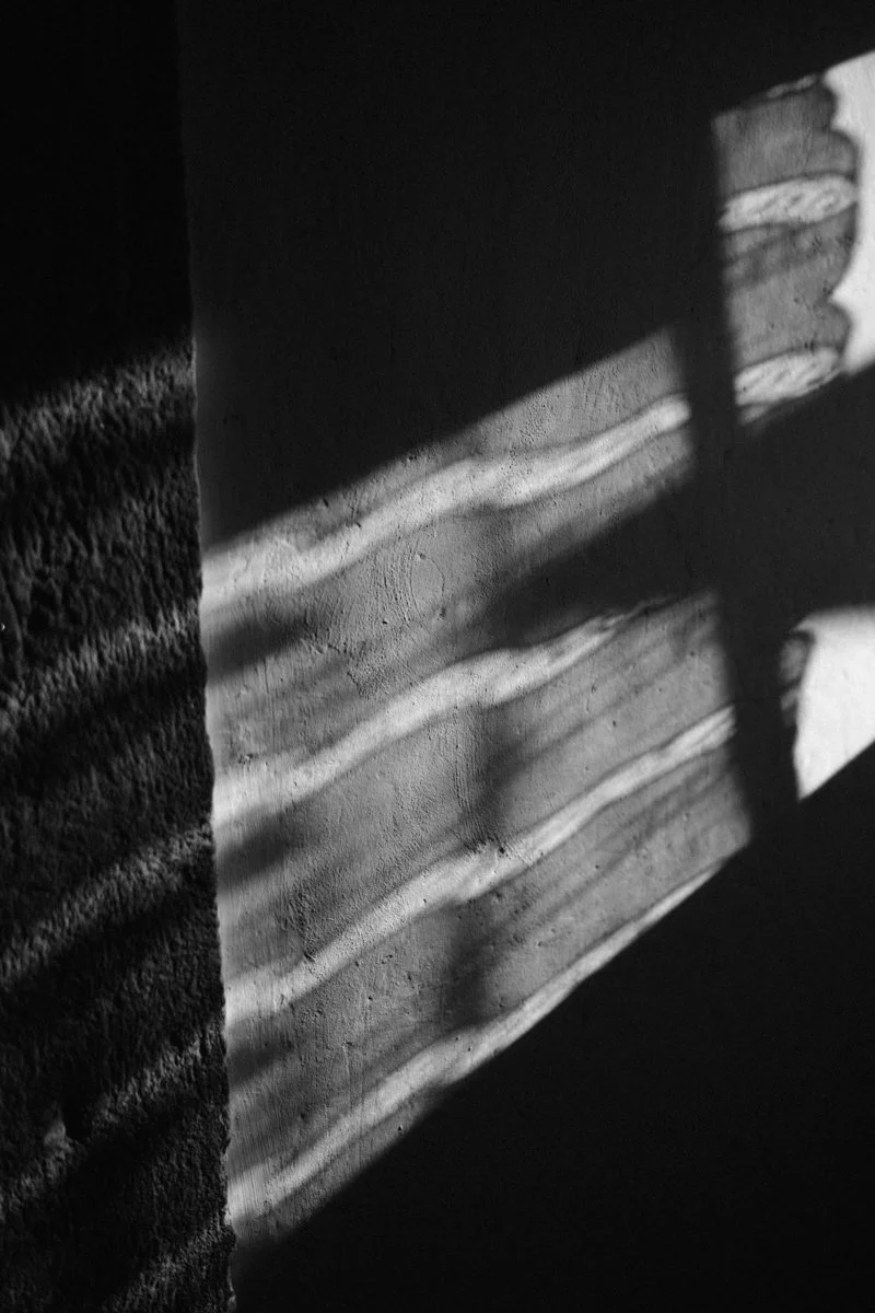 Sunlight creating shadow patterns on a textured wall and floor.