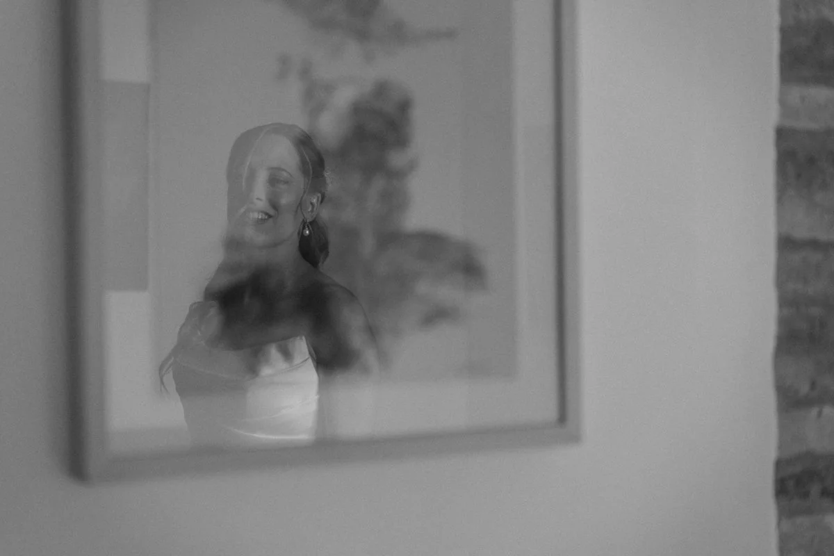 A woman taking a photo of herself through a mirror, seen in a black and white image.