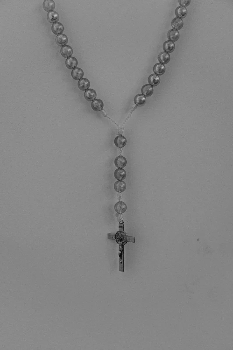 A rosary necklace with beads and a crucifix hanging at the bottom, displayed against a plain background.