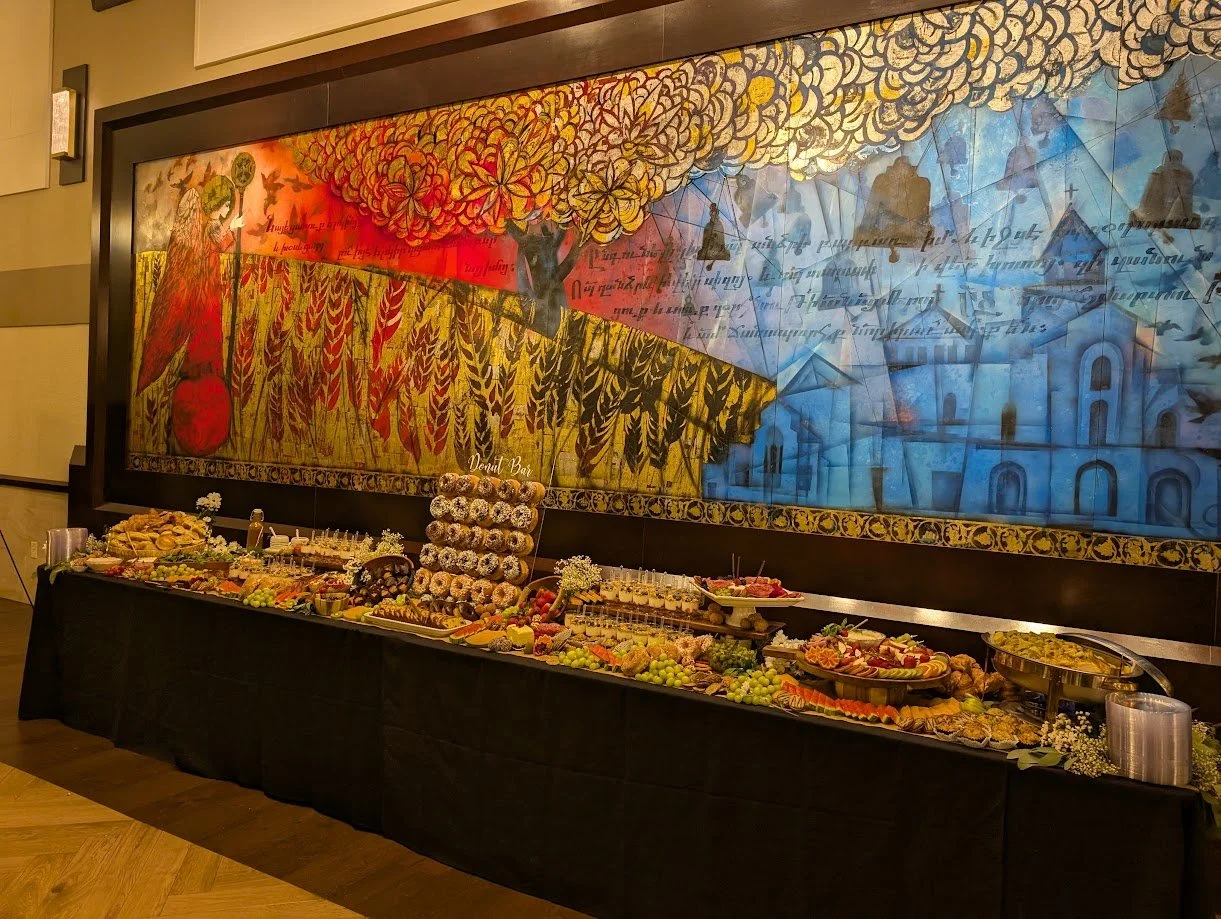 A buffet table set with various dishes and desserts under a large artistic mural in the background.