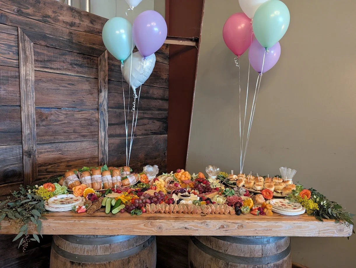 A party table with fruit, snacks, and balloons.